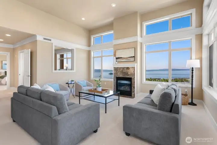 Living area with soaring ceilings, expansive windows, fireplace, and panoramic views.