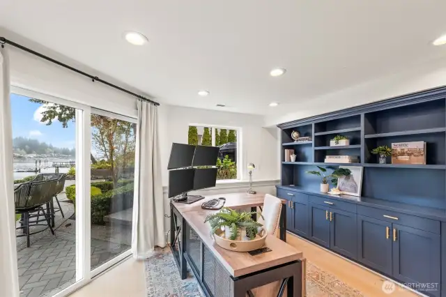 This office of dreams has custom navy built-ins and a sliding glass door leading out to the waters edge