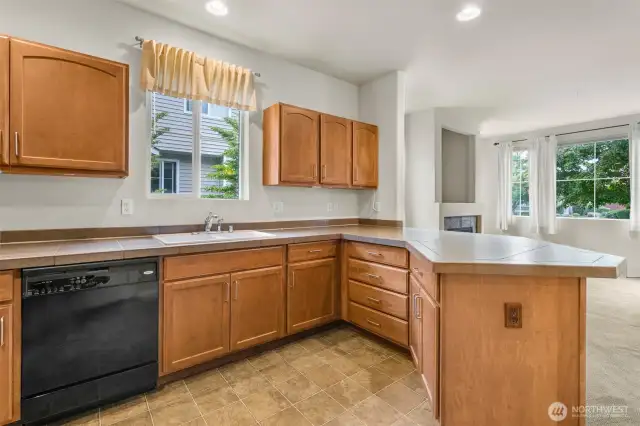 Recessed lighting in the open Kitchen with tile counters. All appliances stay!