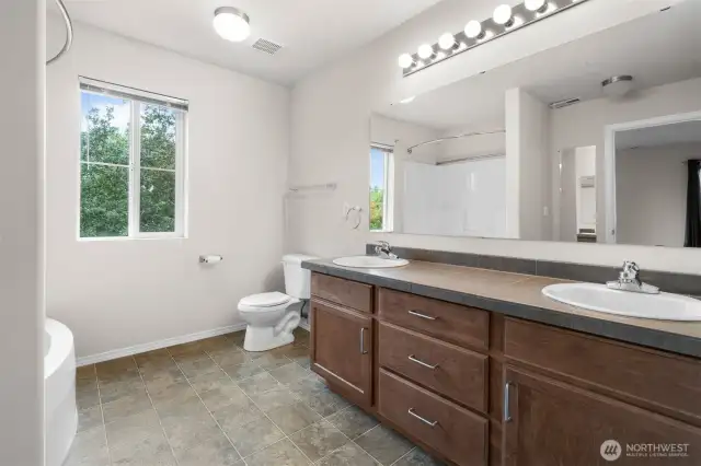 Private Primary Bathroom features large vanity with dual sinks, tile counters. and soaking tub.