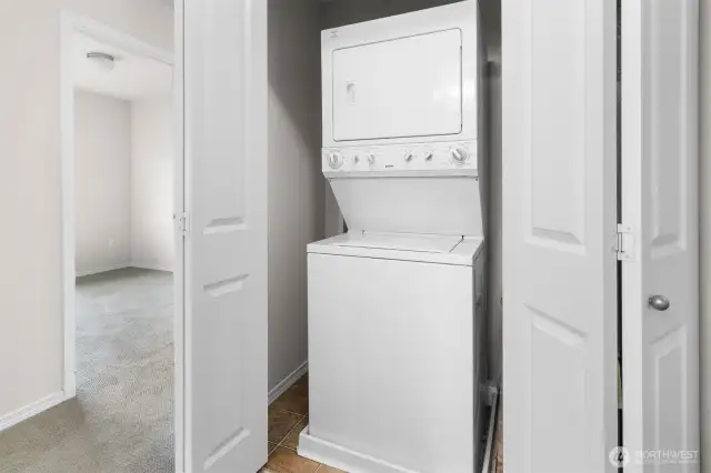 Bi-fold doors open to laundry closet with stacking washer and dryer set.