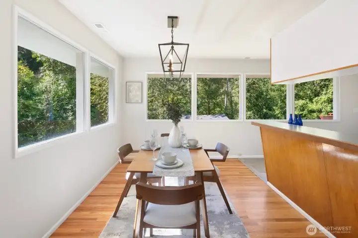 Dining room surrounded by windows overlooking your green backyard.