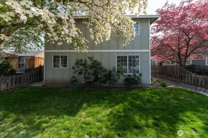 Exterior with landscaped grassy yard and dogwood trees.