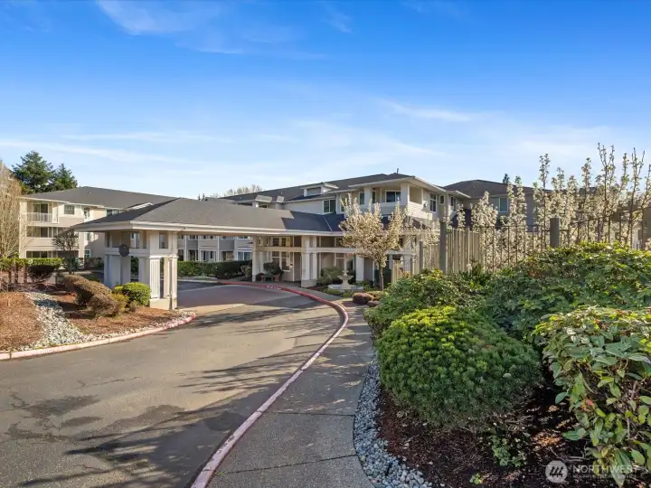 Exterior view of Le Chateau Condominiums with landscaped grounds, private drive, and covered entry in Bellevue’s Woodridge area.