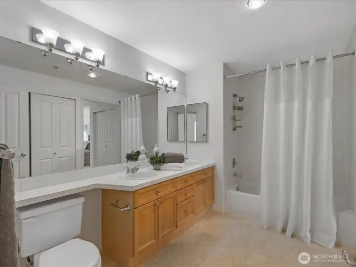 Bathroom with vanity, countertop space, and tub/shower combination. Clean layout with storage and mirror lighting. Connects to first bedroom.