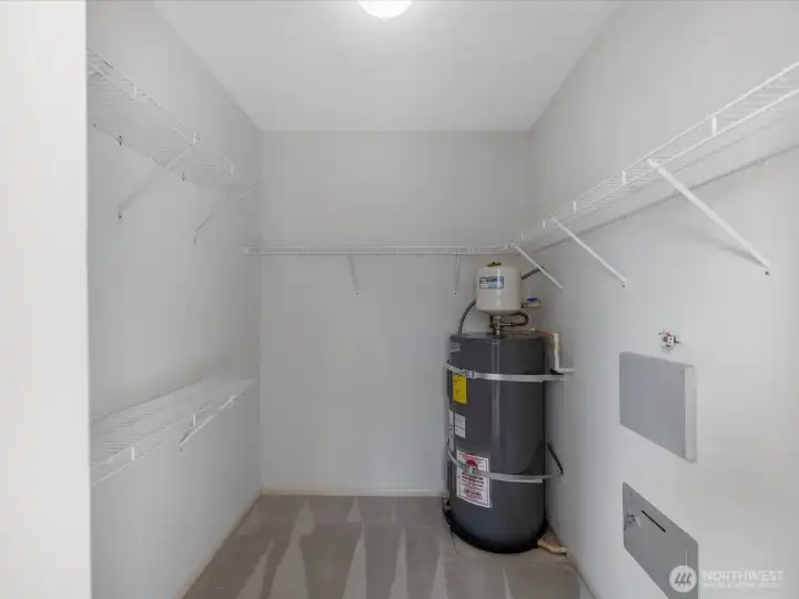 Walk in closet with built-in shelving with ample space, and easy access to the water supply.