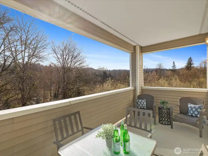 Large private covered deck with extended views of surrounding trees and greenbelt, offering additional outdoor living space with open outlook.