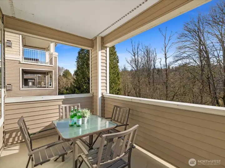 Covered deck with seating area overlooking private wooded greenbelt, providing outdoor space with territorial views and year-round usability.