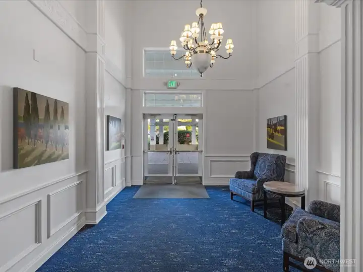 Secure building lobby with high ceilings, seating area, and controlled entry. Main entry point with direct access to interior corridors and elevator.