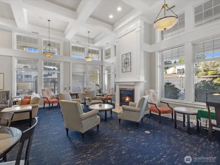 Community clubhouse with high ceilings, fireplace, and multiple seating areas. Shared amenity space with natural light and common gathering areas.