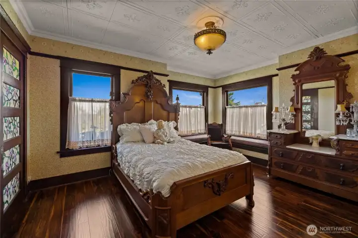 Bedroom #2 on the second floor with glass paneled door to bedroom #1.   Window seats offer great views of the neighbor hood as the home is perched on a high spot.