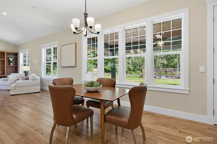 Bright eating area off the kitchen with large windows, warm wood flooring, upgraded lighting, and views toward the covered patio and fenced garden. Bright eating area off the kitchen with large windows, warm wood flooring, upgraded lighting, and views toward the covered patio and fenced garden.