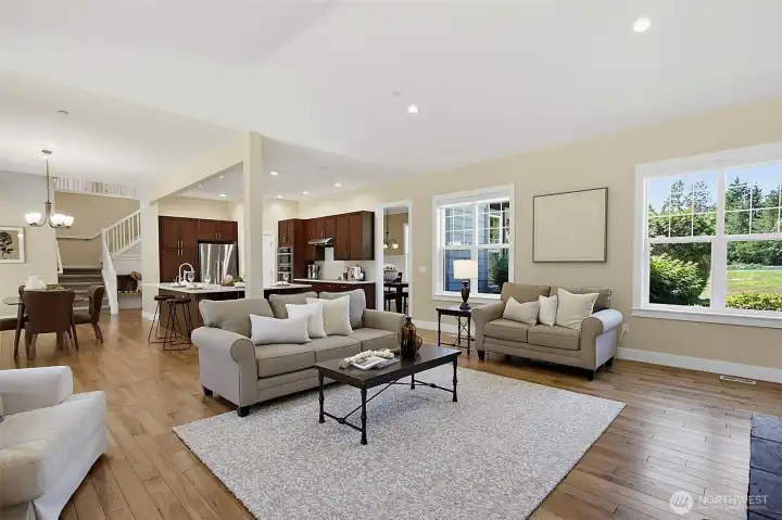 Family room with vaulted ceilings, warm wood flooring, built-in cabinetry, large windows, and a striking stone gas fireplace. Family room with vaulted ceilings, warm wood flooring, built-in cabinetry, large windows, and a striking stone gas fireplace.