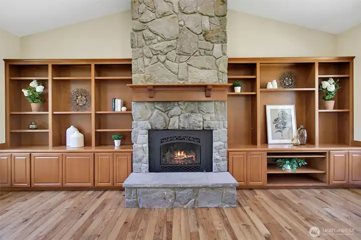 Family room focal point with vaulted ceiling, built-in cabinetry, warm wood flooring, and a striking stone gas fireplace. Family room focal point with vaulted ceiling, built-in cabinetry, warm wood flooring, and a striking stone gas fireplace.