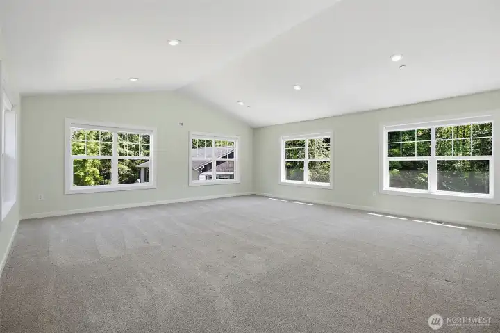 Spacious room with soft carpet, recessed lighting, and multiple windows for natural light. Spacious room with soft carpet, recessed lighting, and multiple windows for natural light.