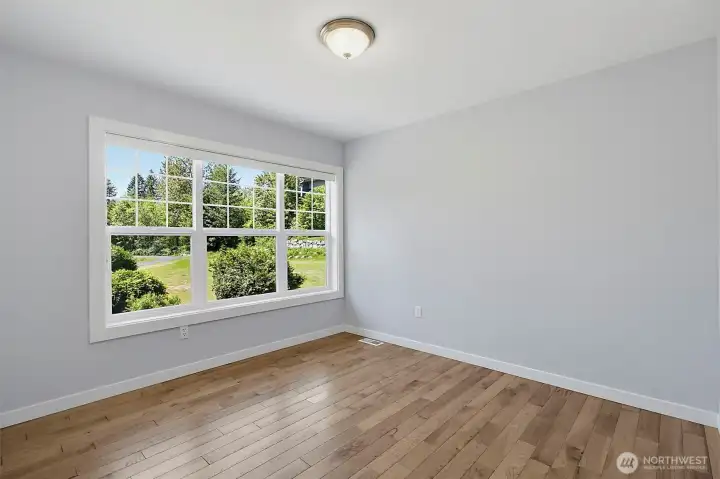 Comfortable bedroom with wood flooring, fresh paint, and a large window overlooking the property. Comfortable bedroom with wood flooring, fresh paint, and a large window overlooking the property.