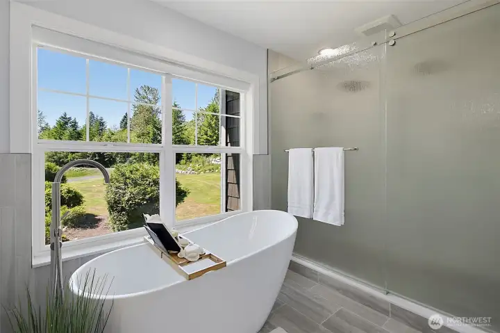 Primary bath with a slipper tub, large window views, new tile flooring, quartz countertops, and solid wood cabinetry. Primary bath with a slipper tub, large window views, new tile flooring, quartz countertops, and solid wood cabinetry.