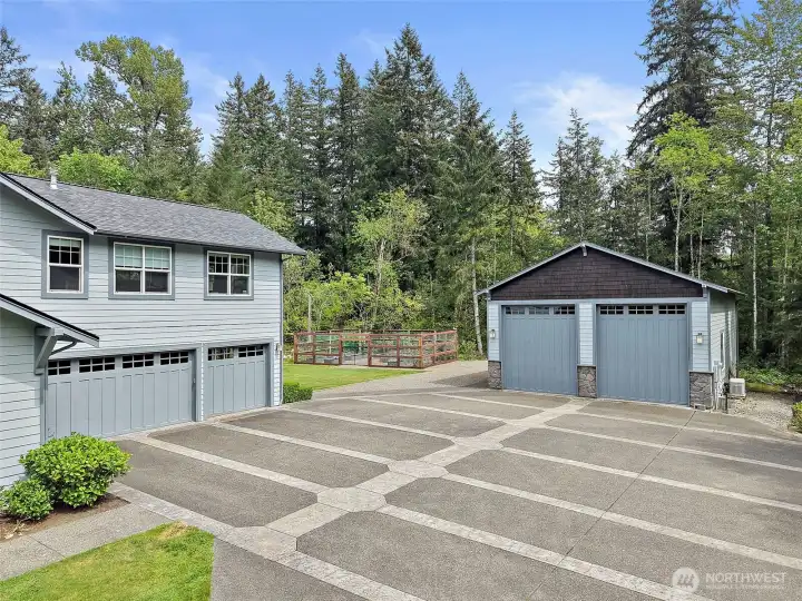 Attached 3-car garage, large two-story shop, and wide paved parking area with the Elk fenced garden and private wooded setting beyond. Attached 3-car garage, large two-story shop, and wide paved parking area with the Elk fenced garden and private wooded setting beyond.