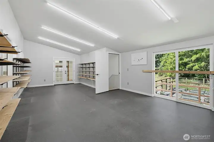 Upper-level shop space with bright lighting, shelving, and room for storage, equipment, or projects. Upper-level shop space with bright lighting, shelving, and room for storage, equipment, or projects.