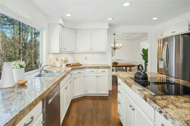 The remodeled kitchen is a chef's dream, boasting gleaming granite countertops, stainless steel appliances, a generous dining nook, ample storage, solid hardwood floors, and a central island perfect for meal prep or casual entertaining.