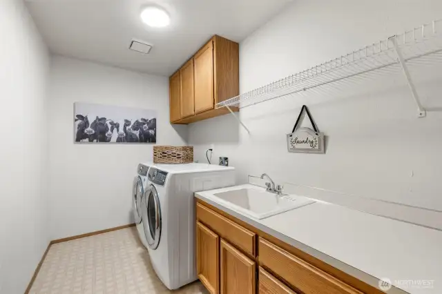 Laundry room with storage cabinets and counter top and utility sink.