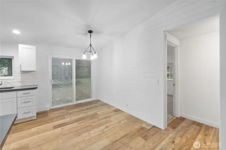 A clear view of the dining area with warm wood flooring, fresh white walls, and sliding doors that open to the backyard. This space gets great natural light and sits just off the kitchen, offering flexibility for everyday meals or a larger dining setup.