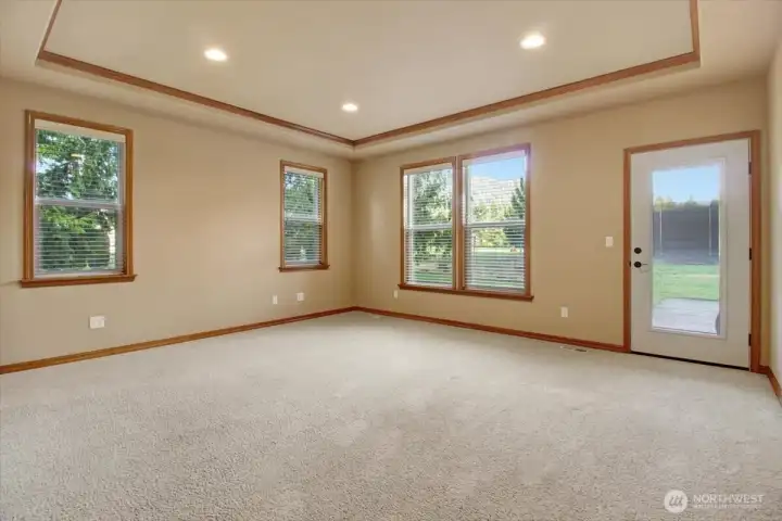 Primary Bedroom with lcoffered ceilings, recessed lightingt and door to rear covered deck & backyard.