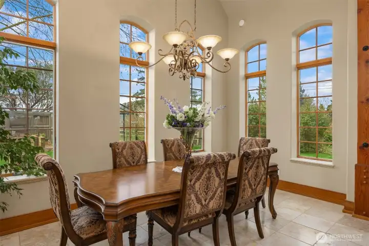Lightfilled dining room is surrounded by immense windows overlooking the back gardens.