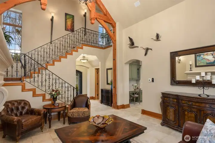Elegant stairway with iron railings echoes the custom iron doors throughout the home. Powder room and arched entry to the kitchen can be seen in this shot.