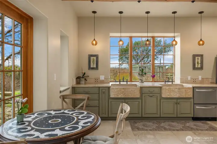 Two limestone farm sinks set in marble counters. Accented with limestone flooring.
