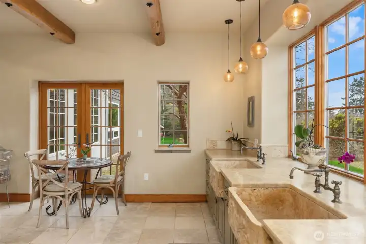 Lightfilled kitchen with old growth fir ceiling beams. The beautiful sinks are served by Portuguese bridge faucets. A delightful place to cook!