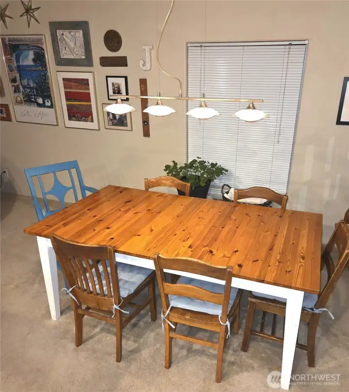 Enjoy meals in a dining room enhanced by custom lighting and a serene garden view of mature rose bushes, adding color and charm throughout the seasons.