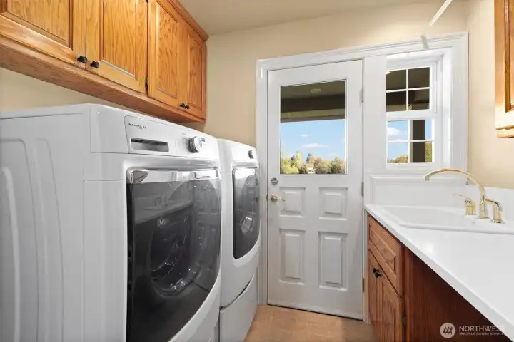 The laundry room is between the kitchen and guest en suite, with built in storage and a utility sink.  Room for laundry baskets under the counter to the right of the sink. Access to the back patio.