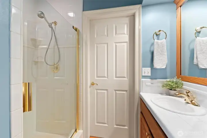 Guest three quarter bath or second primary en suite on main floor.  Shower, single sink and toilet with access from hallway and from the bedroom. Toilet is off camera next to the shower on the left.