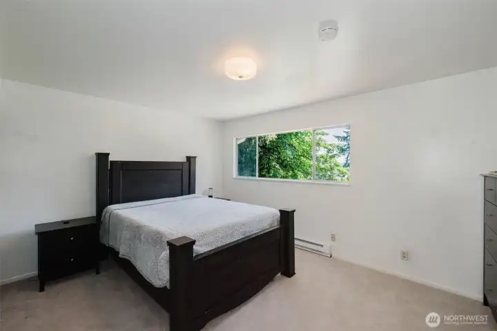 Spacious primary bedroom with peaceful water views and large windows that bring in beautiful natural light, creating a relaxing retreat with a serene atmosphere. Spacious primary bedroom with peaceful water views and large windows that bring in beautiful natural light, creating a relaxing retreat with a serene atmosphere.