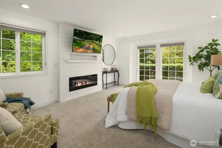 A serene main floor primary suite includes an electric fireplace and calming views of the surrounding gardens. A serene main floor primary suite includes an electric fireplace and calming views of the surrounding gardens.