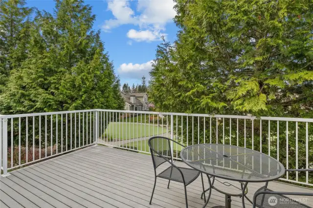 Balcony with seating area and privacy trees.
