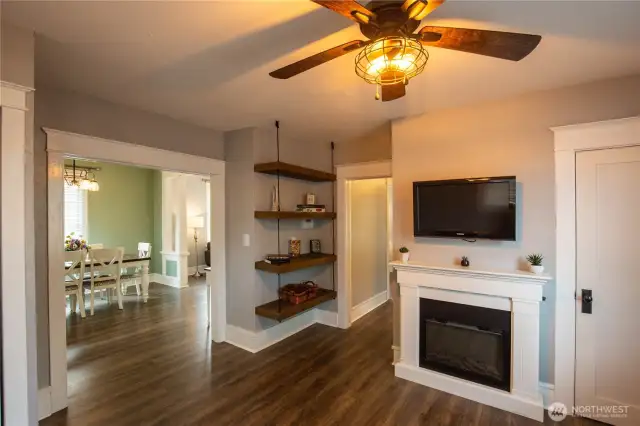 The family / flex room is off the dining room, with an electric fireplace, ceiling fan and custom shelving.