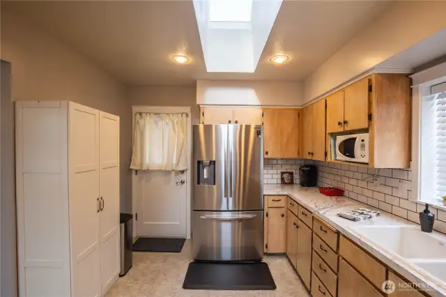 Another view of the kitchen with pantry cabinet and back door to the fenced back yard.