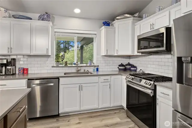 Stainless appliances, white cabinetry and quartz countertops w/subway tile give this kitchen a modern farmhouse vibe.