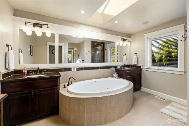 View of tile and granite 5 piece master bath with garden jetted soaking tub, large horizontal mirrors, skylights and oil rubbed bronze lighting.