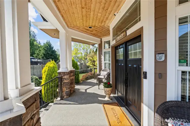 Welcoming covered front porch as you enter home with stone columns, black wroght iron railings, French front doors, pine wood soffits and recessed lighting to enjoy year around.