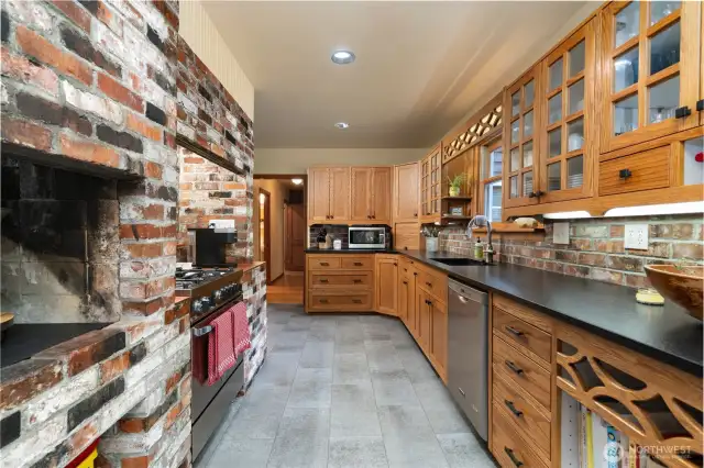 Galley style kitchen with original brickwork, custom cabinets, granite countertops and stainless-steel appliances.