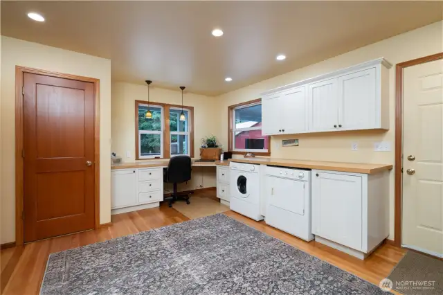 Spacious laundry room with corner office workspace.