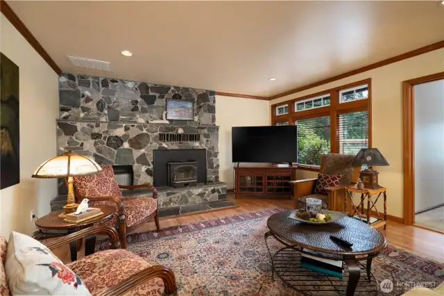 Main floor living room with wood insert fireplace, rock surround and wood flooring.