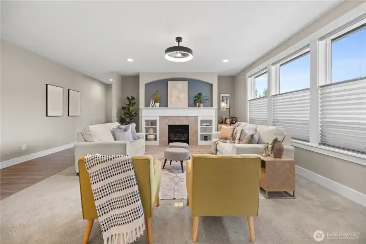Bright and inviting great room with a gas fireplace, custom mantel, arched accent niche, and large windows for natural light