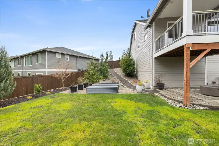 A functional backyard setup with a covered upper deck, lower patio area, and space to relax, play, or entertain