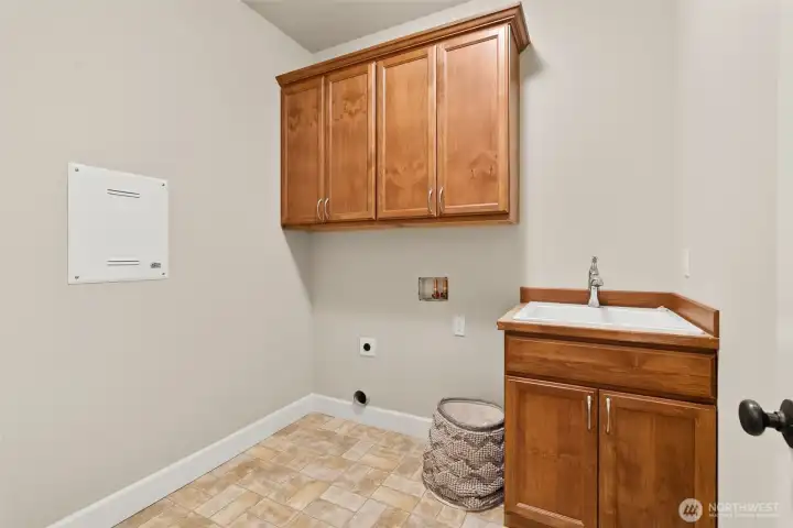 Separate laundry room with sink and storage on the main level