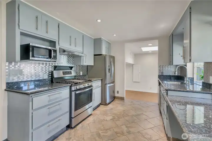 Modern Kitchen with tile backsplash, grey cabinetry and stainless steel appliances.