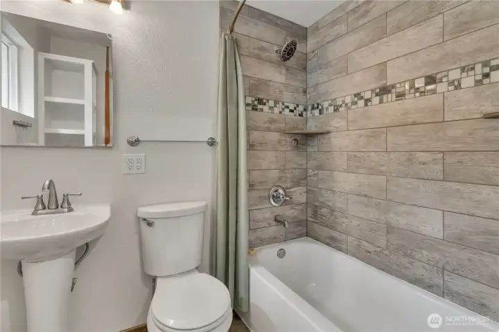 Full bath with with custom tile and pedestal sink.